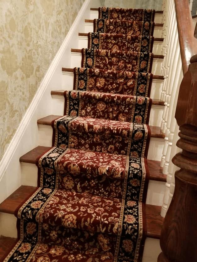 Ornate red and gold floral-pattern carpet runner hand-fit to a straight staircase